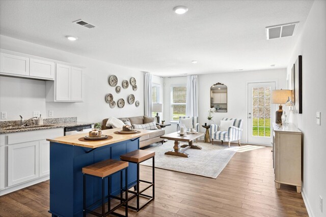 kitchen featuring a kitchen island, dark wood-type flooring, stainless steel dishwasher, sink, and white cabinets