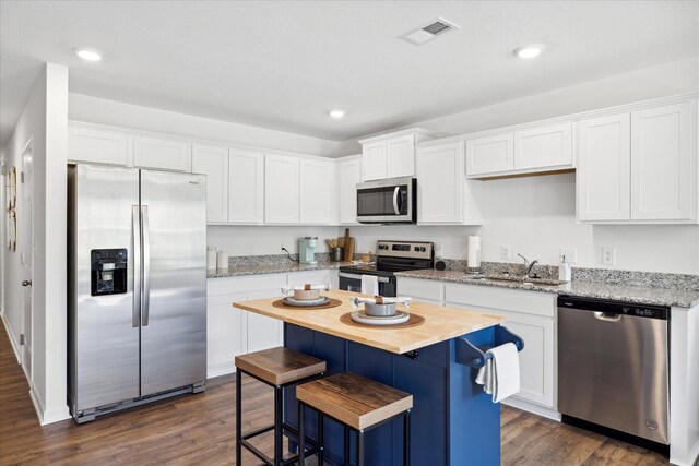 kitchen featuring white cabinets, appliances with stainless steel finishes, a kitchen island, and dark hardwood / wood-style floors