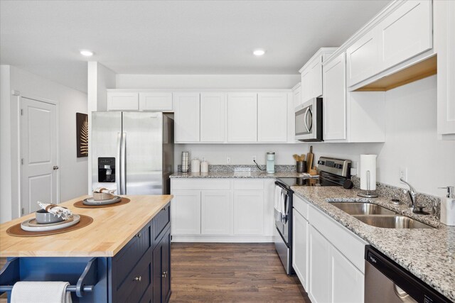 kitchen featuring white cabinets, light stone countertops, stainless steel appliances, sink, and dark wood-type flooring