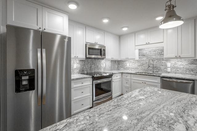 kitchen with light stone counters, hanging light fixtures, stainless steel appliances, and sink