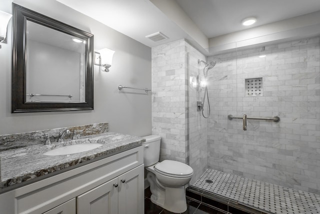 bathroom with visible vents, tiled shower, toilet, and vanity