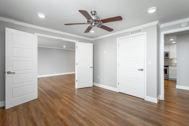 unfurnished room featuring wood finished floors, crown molding, a ceiling fan, and visible vents