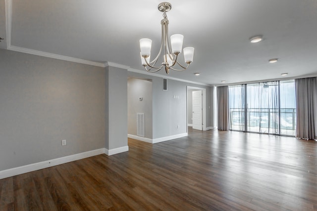 spare room with crown molding, dark wood-type flooring, an inviting chandelier, and a wall of windows