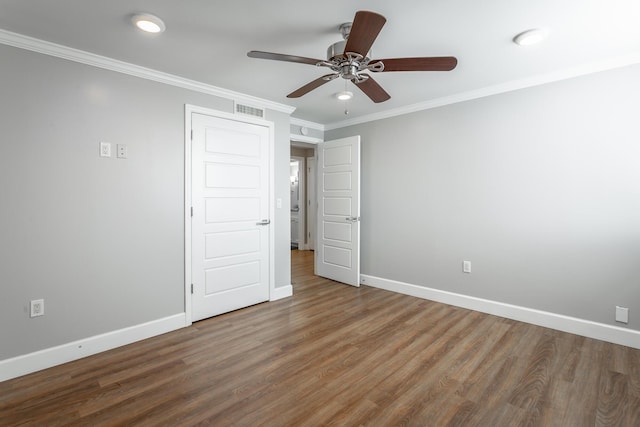 unfurnished bedroom featuring a ceiling fan, wood finished floors, baseboards, visible vents, and ornamental molding