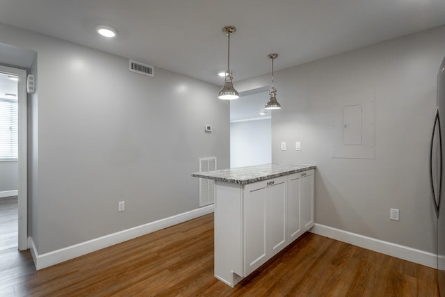 kitchen featuring kitchen peninsula, hardwood / wood-style floors, white cabinetry, and decorative light fixtures