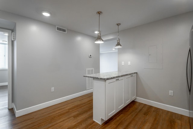 kitchen with a peninsula, wood finished floors, and visible vents