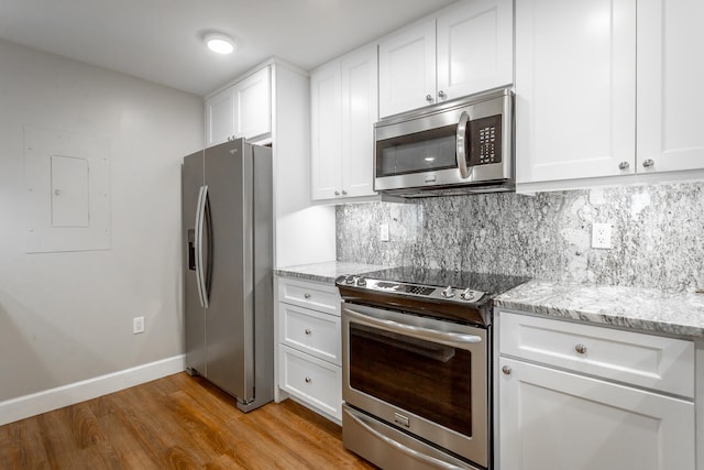 kitchen with hardwood / wood-style floors, light stone counters, stainless steel appliances, and white cabinetry