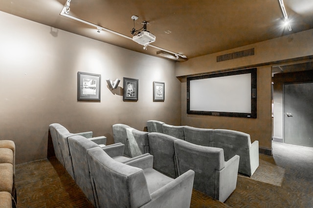 cinema room featuring track lighting and dark colored carpet