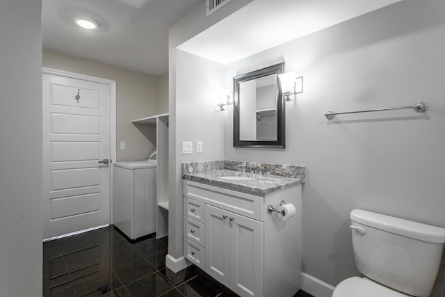 bathroom featuring tile patterned floors, toilet, washer / clothes dryer, and vanity