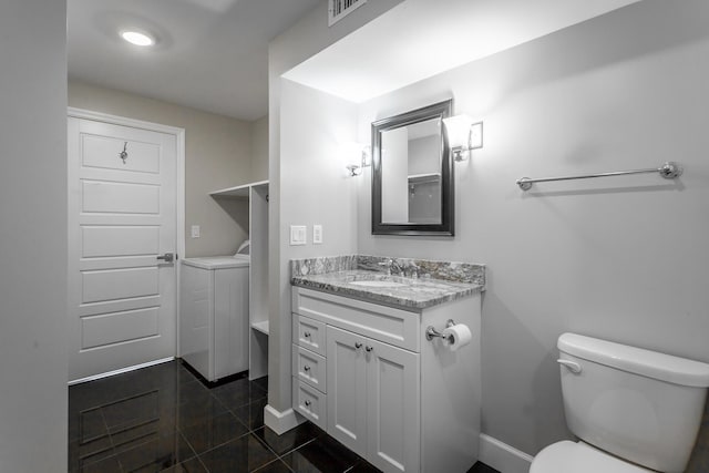 bathroom with visible vents, toilet, baseboards, washer / dryer, and vanity