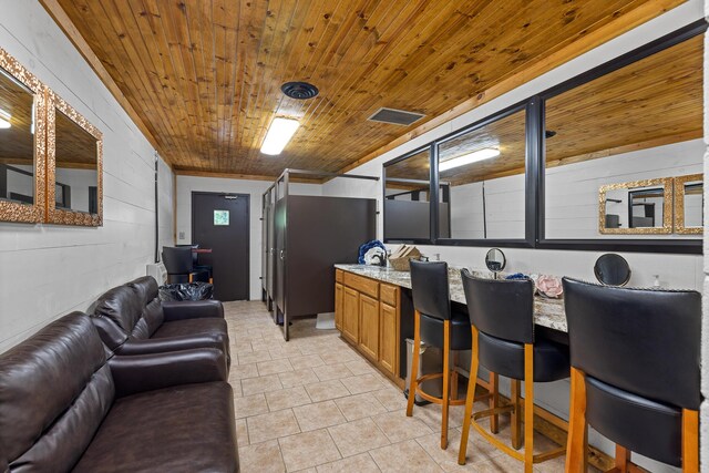 interior space with wood ceiling, light tile patterned floors, and light stone countertops