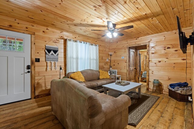 living room featuring wood ceiling, light hardwood / wood-style flooring, ceiling fan, and wooden walls