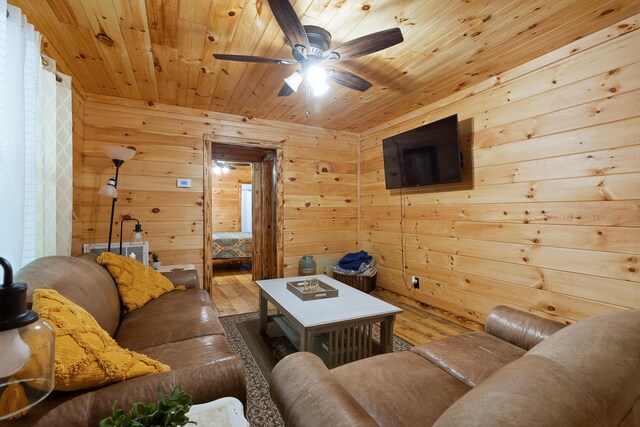 living room with wooden ceiling, light hardwood / wood-style flooring, ceiling fan, and wooden walls