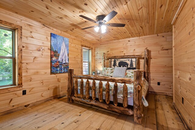 bedroom featuring wooden ceiling, light hardwood / wood-style flooring, ceiling fan, and wooden walls