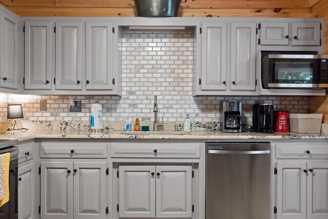 kitchen with light stone countertops, stainless steel appliances, white cabinetry, sink, and decorative backsplash