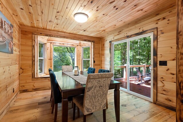 dining space with wooden ceiling, a wealth of natural light, wooden walls, and light hardwood / wood-style floors