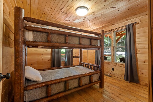 bedroom with wood-type flooring, wood ceiling, and wooden walls