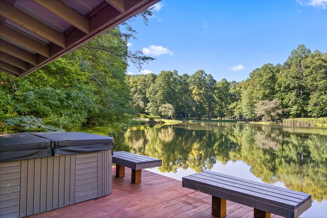 view of dock with a hot tub and a deck with water view