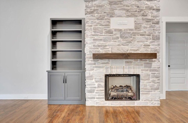 unfurnished living room featuring hardwood / wood-style flooring and a stone fireplace