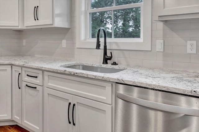 kitchen with dishwasher, sink, light stone countertops, and white cabinets