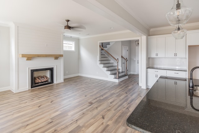 kitchen with ceiling fan, ornamental molding, dark stone counters, white cabinetry, and light wood-type flooring