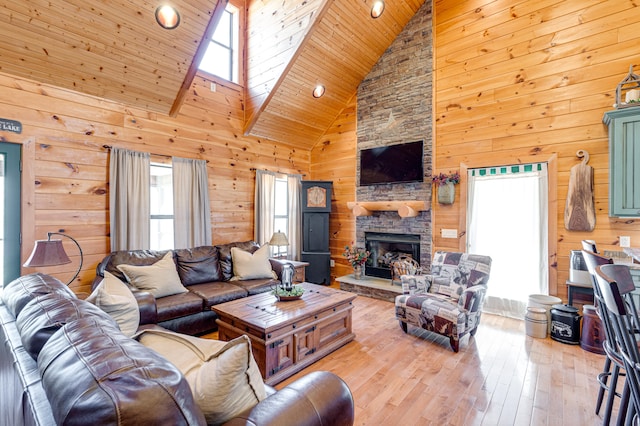 living room featuring wooden ceiling, a fireplace, light hardwood / wood-style floors, high vaulted ceiling, and wooden walls