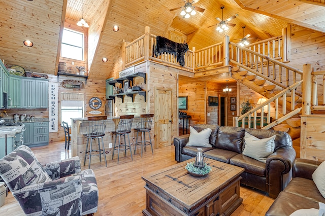 living room with light wood-type flooring, ceiling fan, plenty of natural light, and a high ceiling