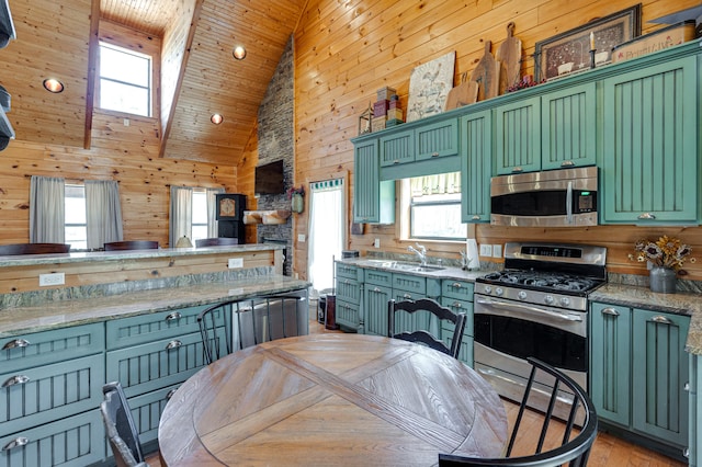 kitchen with appliances with stainless steel finishes, high vaulted ceiling, plenty of natural light, and green cabinets