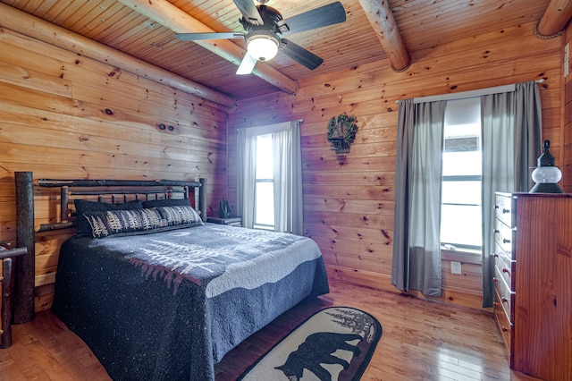 bedroom with wooden ceiling, hardwood / wood-style floors, beam ceiling, ceiling fan, and wooden walls