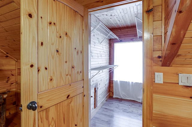 hall with wood walls, wooden ceiling, and light hardwood / wood-style flooring