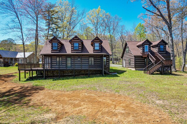 rear view of property featuring a wooden deck and a lawn