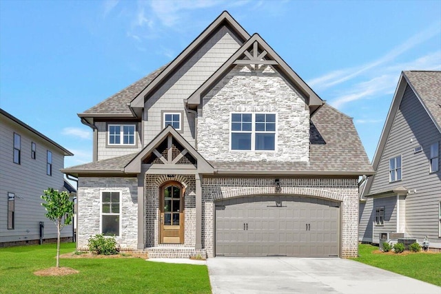 craftsman-style house featuring stone siding, a front lawn, driveway, and a shingled roof