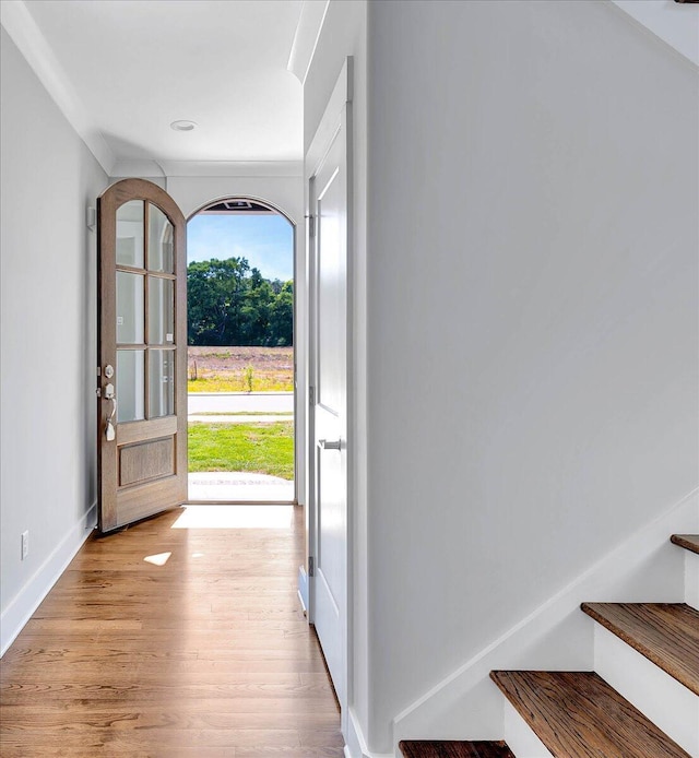 foyer entrance featuring baseboards, light wood-style flooring, and stairs