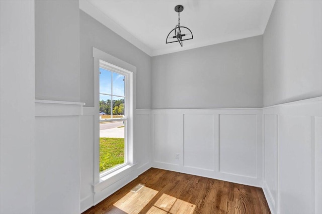 unfurnished dining area with hardwood / wood-style floors, an inviting chandelier, and ornamental molding