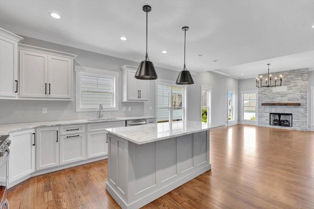 kitchen featuring a kitchen island, a fireplace, light hardwood / wood-style flooring, sink, and white cabinetry