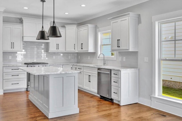 kitchen with a kitchen island, stainless steel dishwasher, sink, white cabinetry, and light wood-type flooring