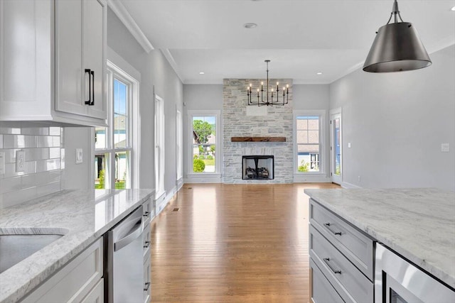 kitchen featuring beverage cooler, ornamental molding, a stone fireplace, stainless steel dishwasher, and light wood-type flooring