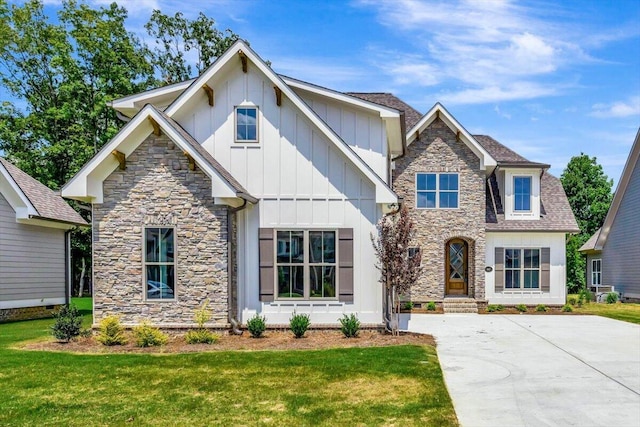 craftsman inspired home featuring a front yard, board and batten siding, and roof with shingles