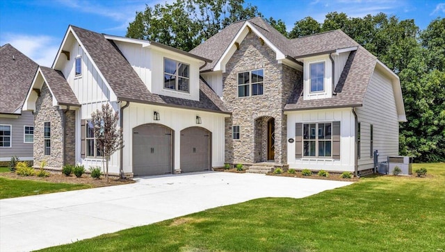 view of front of property featuring driveway, a front lawn, stone siding, roof with shingles, and board and batten siding