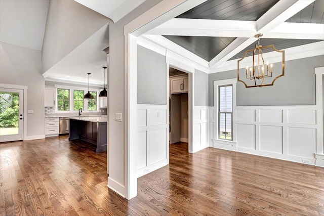 interior space with a wainscoted wall, vaulted ceiling with beams, dark wood-style flooring, a decorative wall, and a chandelier