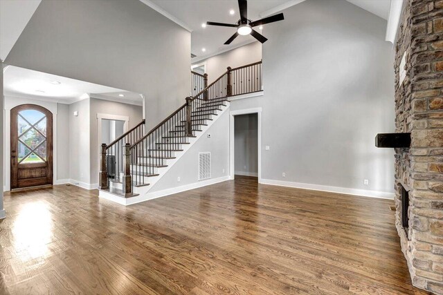 interior space featuring stairway, wood finished floors, visible vents, a fireplace, and a towering ceiling