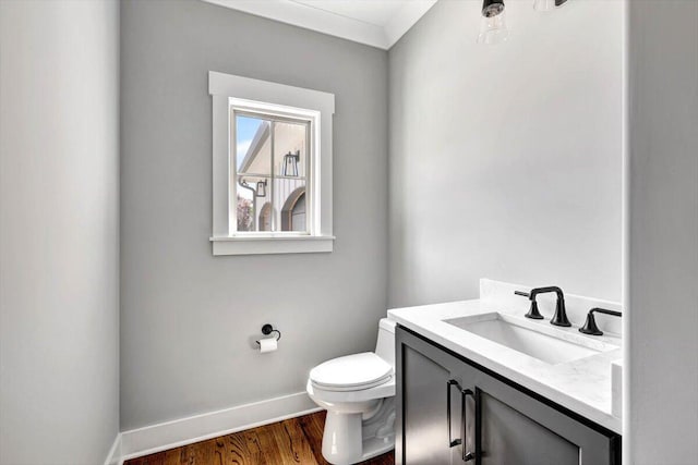 half bath featuring baseboards, toilet, wood finished floors, and vanity