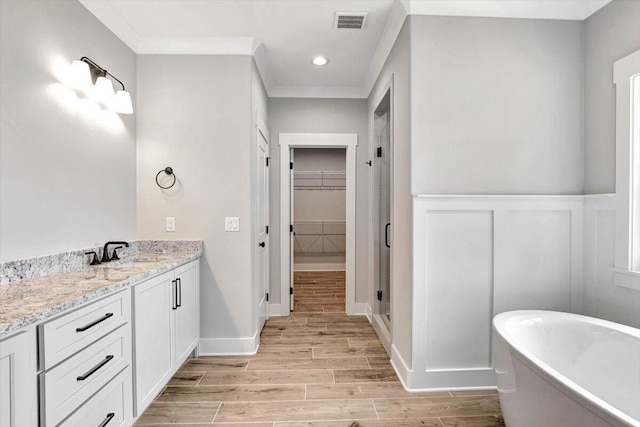 bathroom with visible vents, wood finish floors, a freestanding tub, a stall shower, and a spacious closet