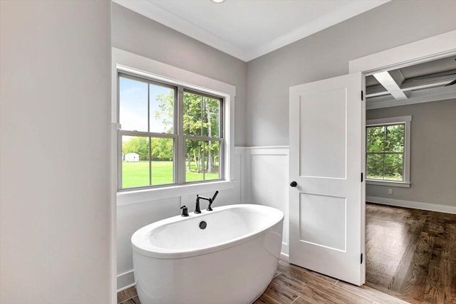 full bath featuring a freestanding tub, coffered ceiling, a healthy amount of sunlight, and wood finished floors