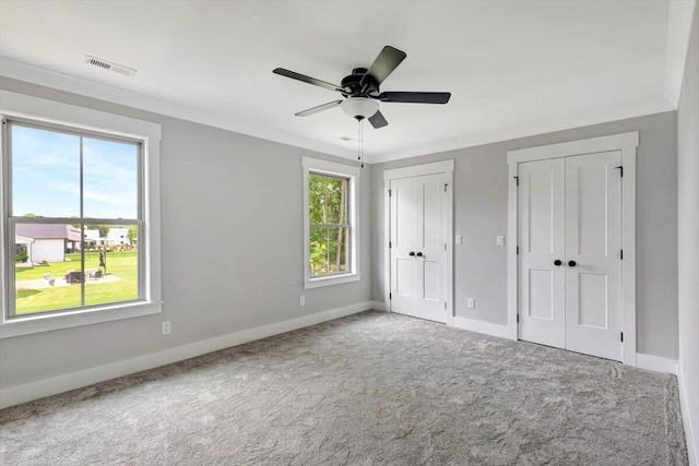 unfurnished bedroom featuring multiple windows, multiple closets, visible vents, and carpet flooring