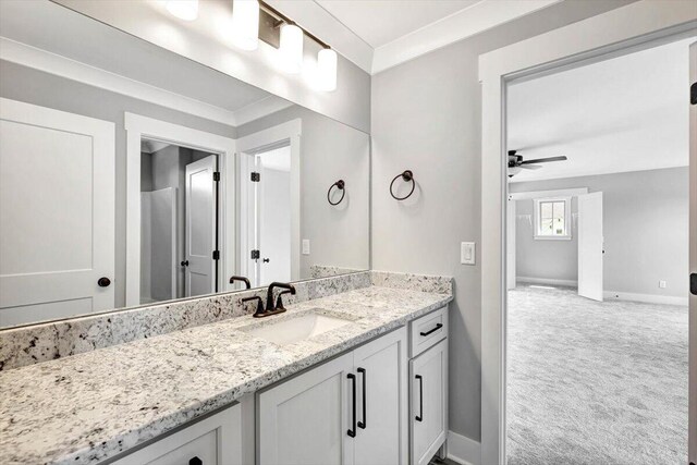 bathroom featuring ceiling fan, baseboards, ornamental molding, and vanity