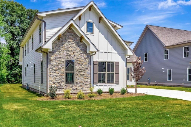 view of front of home featuring stone siding, board and batten siding, and a front lawn