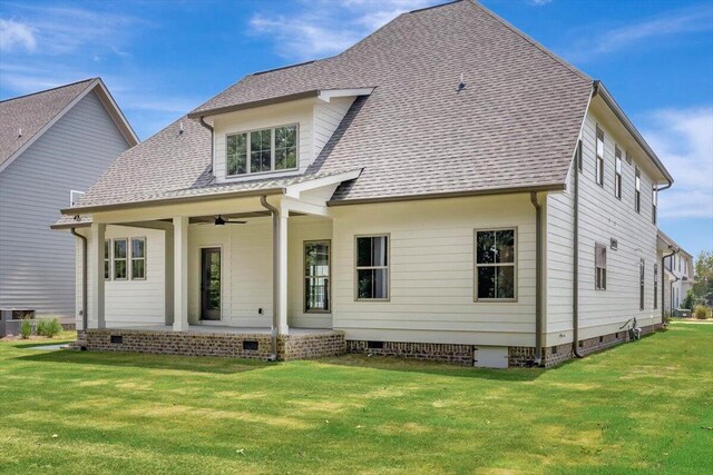 rear view of property featuring a ceiling fan, a lawn, roof with shingles, and crawl space