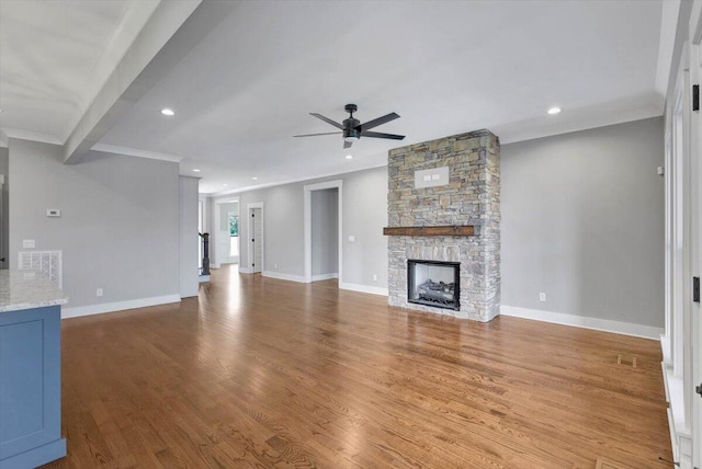 unfurnished living room with a fireplace, crown molding, hardwood / wood-style flooring, and ceiling fan