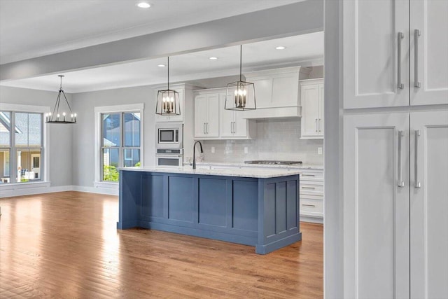 kitchen featuring light wood-type flooring, tasteful backsplash, appliances with stainless steel finishes, white cabinets, and custom exhaust hood